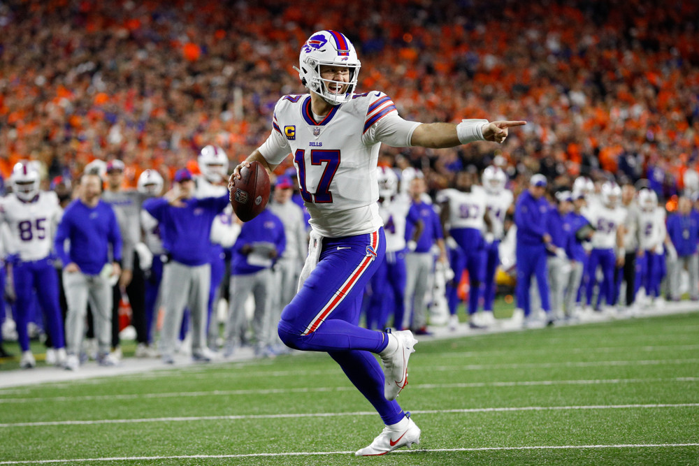 Josh Allen - in white jersey and blue pants- points as he runs in the open field down the sideline