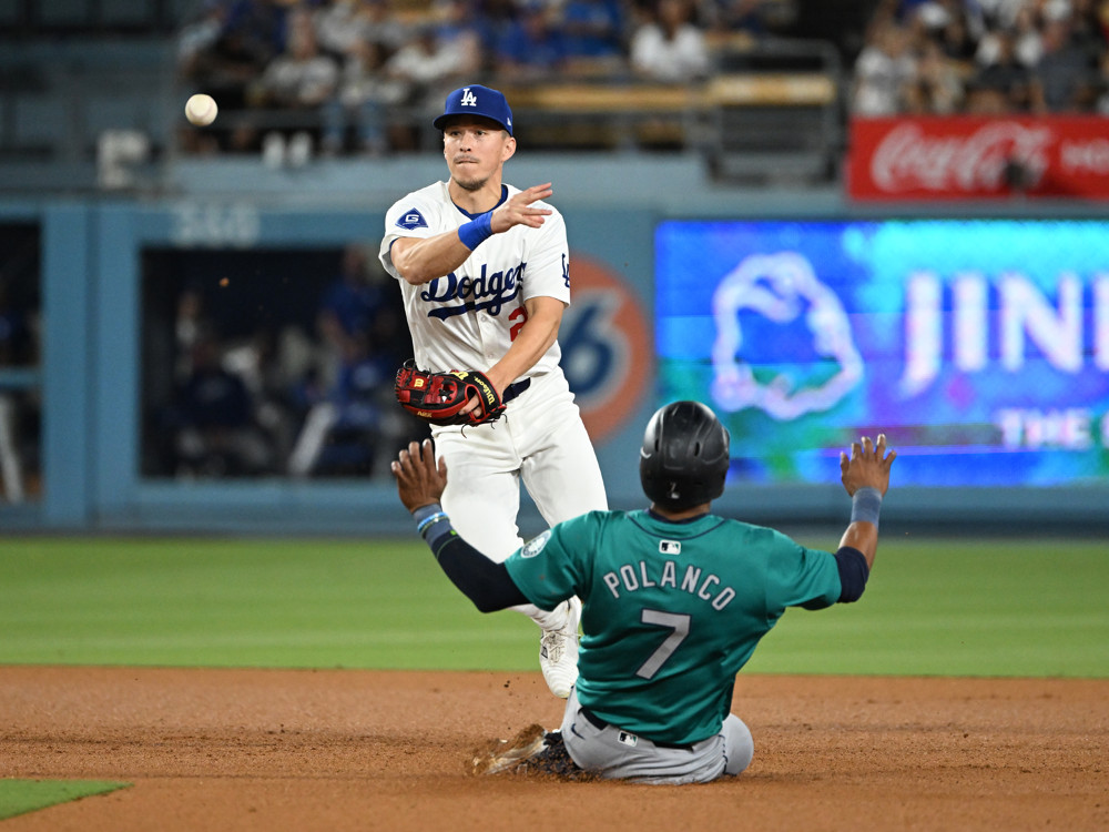 Tommy Edman avoid a sliding runner as he throws to first base to try to complete a double play.