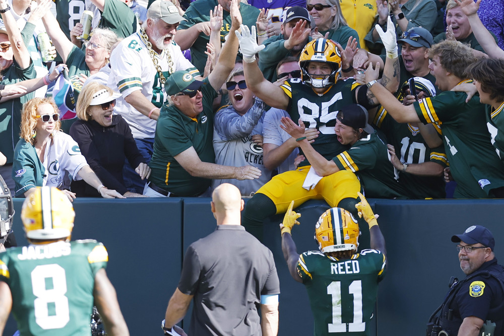 Tucker Kraft sits in the stands with Packers fans after doing a "Lambeau Leap" to celebrate a touchdown