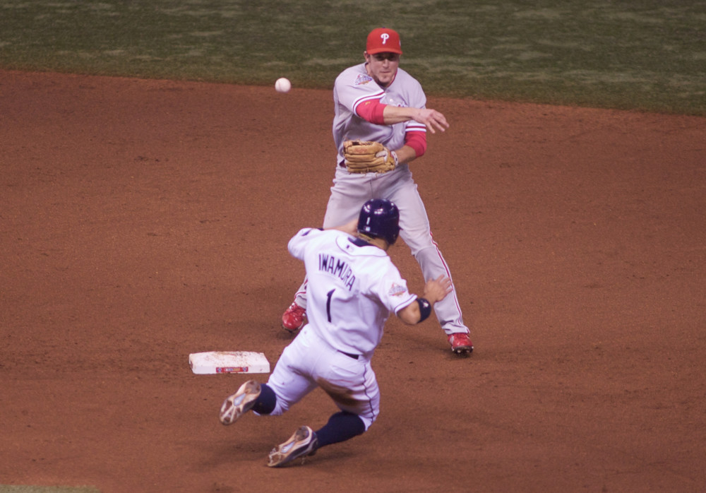 Chase Utley throws to first base with a runner bearing down on him.