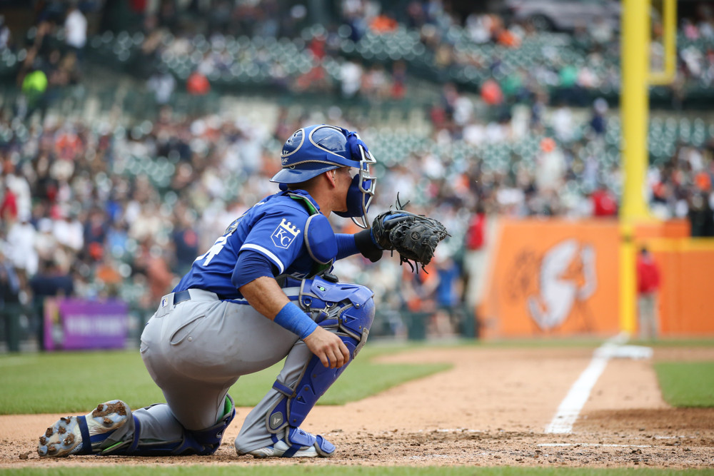 Freddy Fermin, wearing a blue jersey and blue shin guards and a blue helmet, prepares to catch a pitch.