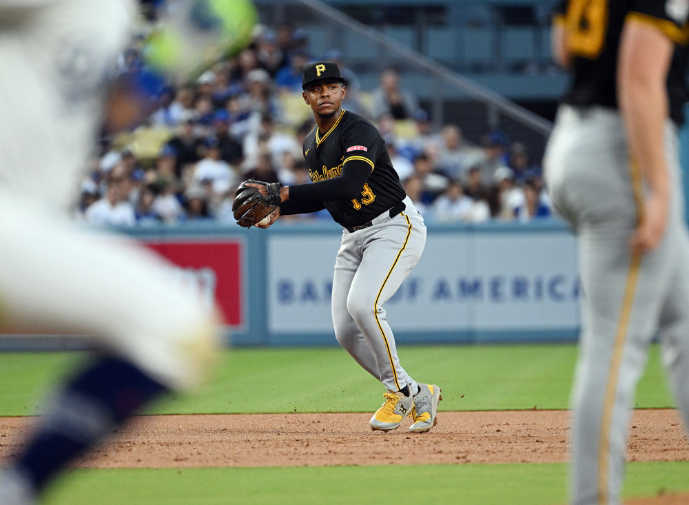 Ke'Bryan Hayes prepares to make a throw to first base, taking the ball out of his glove.