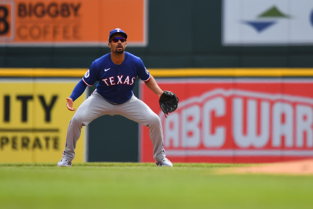 Marcus Semien stands in a ready position, knees bent, arms and legs spread wide, waiting for a ball to be hit to him.