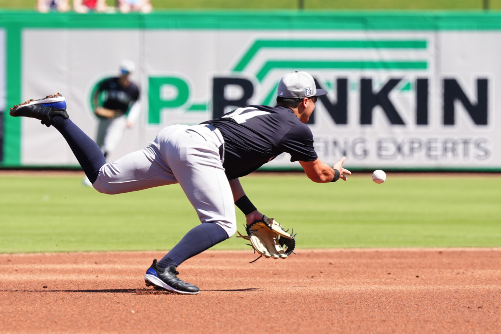 Anthony Volpe dives towards second base as he flips the ball there underhanded to get an out.