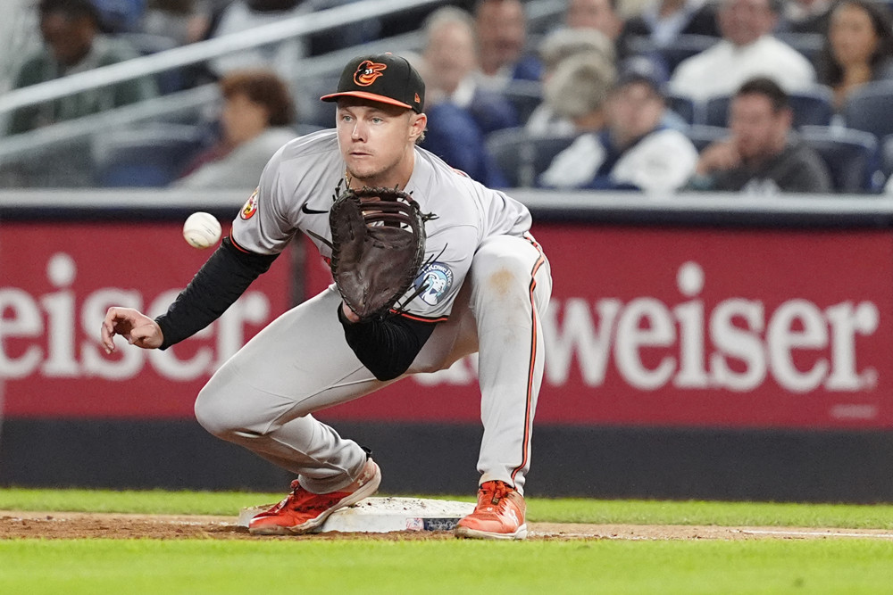 Ryan Mountcastle has 2 feet on first base as he crouches to catch a throw from a teammate.