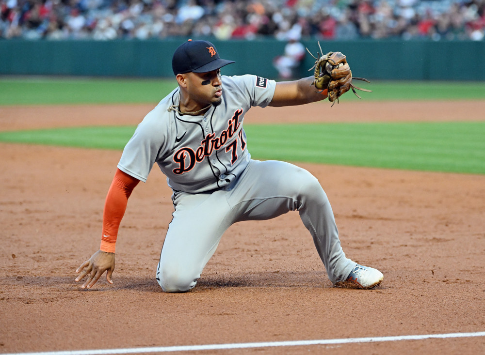 Andy Ibanez goes to one knee and one hand on the dirt to field a ground ball along the 3rd base line.