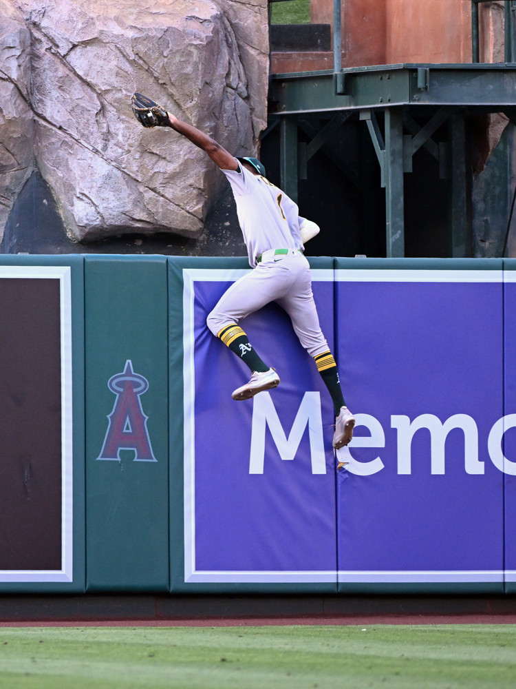 Denzel Clarke reaches well above the top of the center field fence at Angels Stadium to grab a potential home run