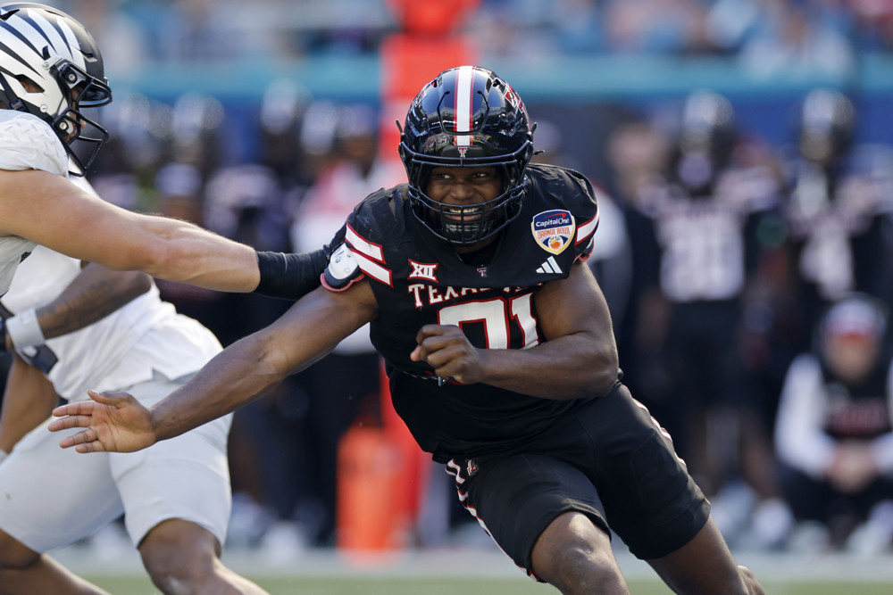 Texas Tech's David Bailey, in a black uniform and helmet with white lettering, moves aggressively around a player attempting to grab him