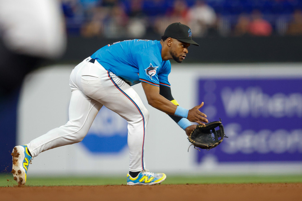 Otto Lopez, in a teal blue Marlins jersey and white baseball pants with a black cap, prepares to field a ground ball at shortstop.